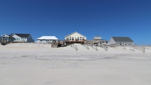 Une propriété située en bord de mer, comprenant plusieurs maisons, des allées en bois et une plage de sable.