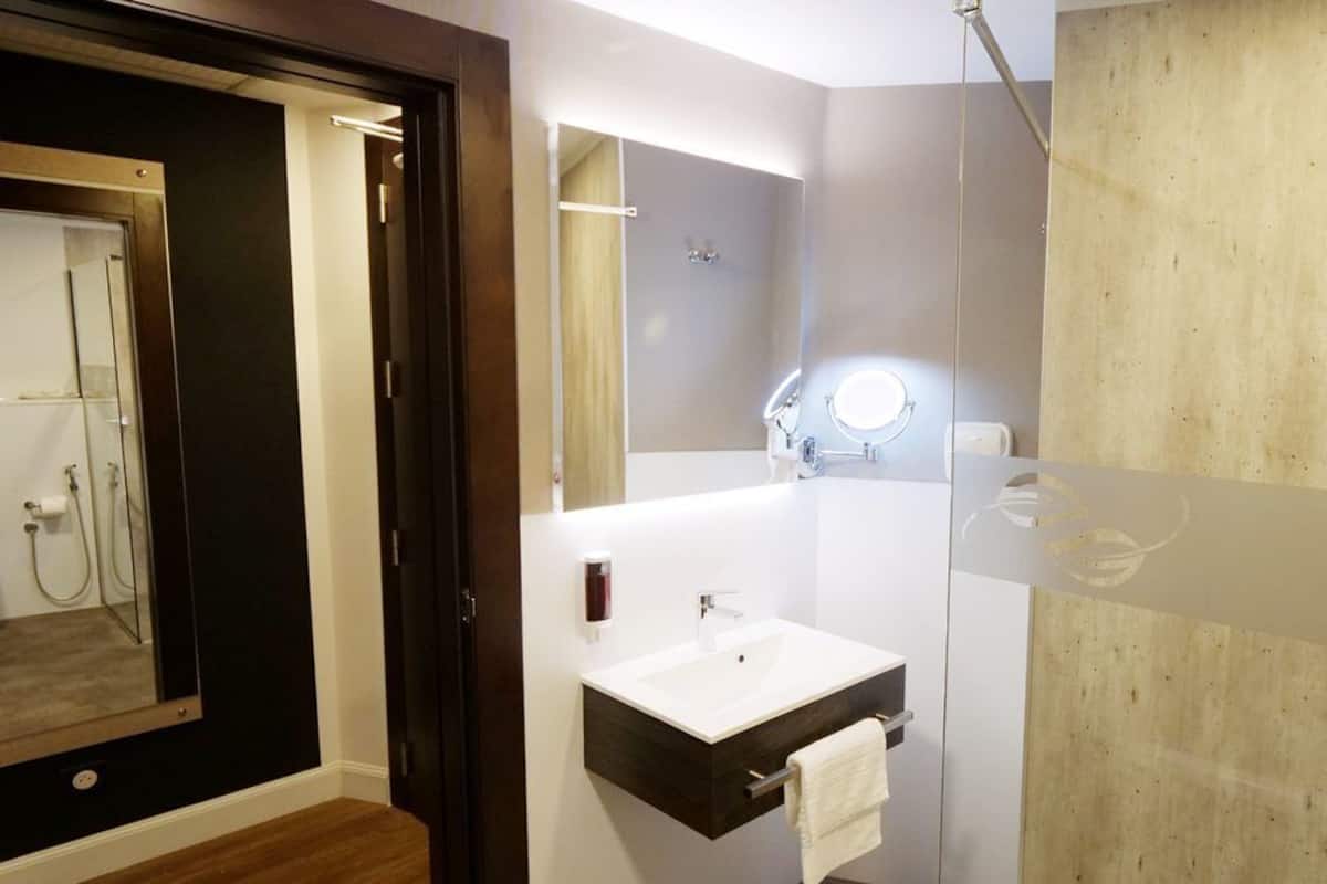 A modern bathroom with a large mirror, a sink, and a shower.