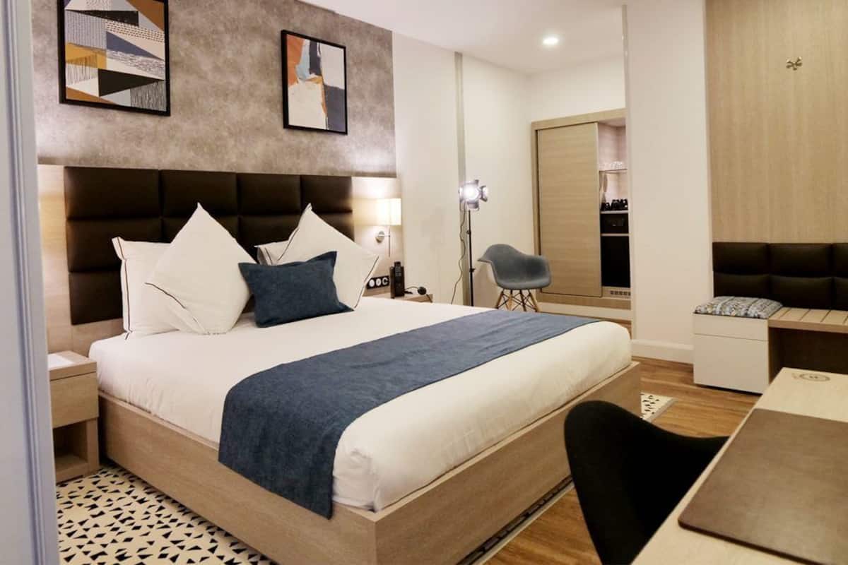 A modern hotel room with a large bed, a desk, and a seating area.
