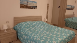 Une chambre à coucher avec un lit, une table de chevet, une lampe, un miroir et un tableau représentant un phare.