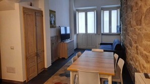 Un espace de vie compact comprenant un coin repas, un téléviseur et un mur en pierre.