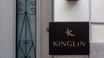 A building entrance with a decorative glass door, a black sign with the name "Kinglin", and a wall-mounted light fixture.
