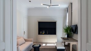 A modern living room with a sofa, coffee table, and a black entertainment unit. - Kinglin Luxury Living (Athens)