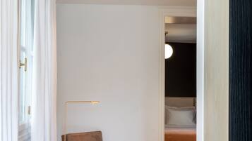 A modern bedroom with a bed, a chair, a floor lamp, and a striped rug.