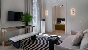 A modern living room with a flat-screen TV, a bench, a coffee table, and a sofa. - Kinglin Luxury Living (Athens)