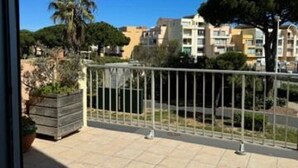 A balcony with a metal railing, a potted plant, and a view of residential buildings. - T2 apartment with large terrace (Gruissan)