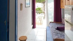 A small room with a bed, a stool, a window, and a door. - T2 apartment with large terrace (Gruissan)