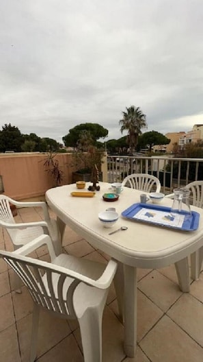 A round table with chairs on a rooftop terrace, with a tray and some dishes on it.
