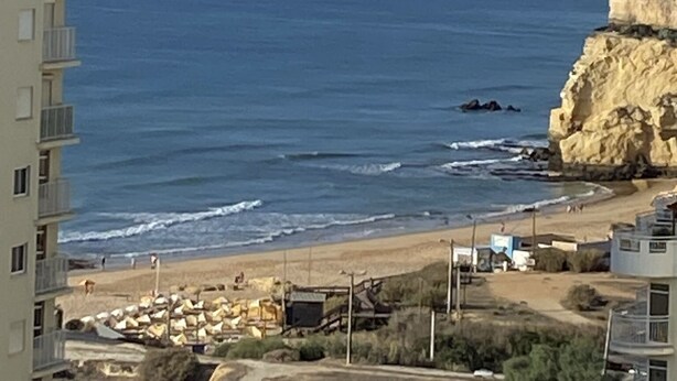 A coastal view with a building on the left and a rocky cliff on the right. - Armação Pêra magnificent sea view 100m from the beach (Armação de Pêra)