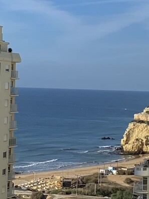 A coastal view with a building on the left and a rocky cliff on the right.