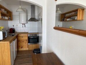A compact kitchen with wooden cabinetry, a built-in oven, a toaster, and a sink.