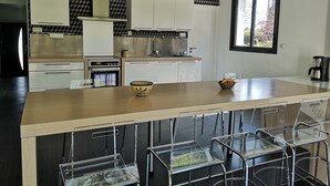 A modern kitchen with a central island, stainless steel appliances, and a black and white patterned backsplash.