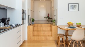 A modern kitchen with white cabinets, a coffee machine, and a dining area with a wooden table and chairs.