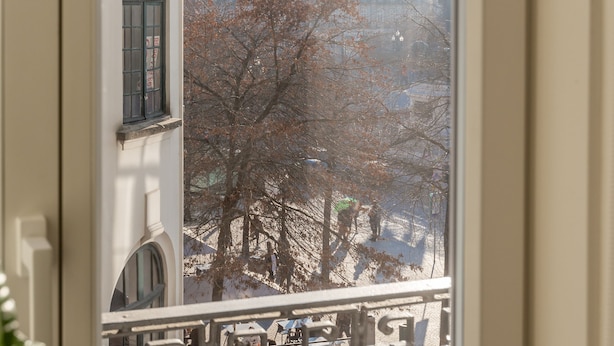 A balcony with a view of a cityscape, including buildings and trees.