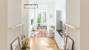 A spacious hallway with wooden flooring, a modern light fixture, and potted plants.