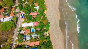 Una vista aerea di una proprietà costiera con spiaggia, case e piscina.