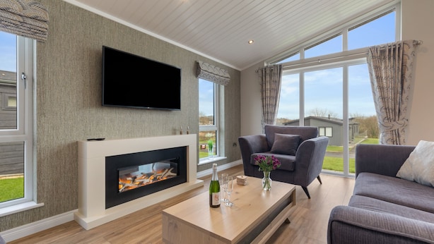 Una sala de estar moderna con chimenea, un televisor de pantalla plana y un amplio ventanal con cortinas.