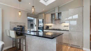 Una cocina moderna con una isla grande, electrodomésticos de acero inoxidable y un tragaluz.