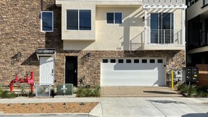 A multi-story residential building with a stone facade, multiple windows, and a garage. - Oceanside beach retreat 3 min walk to beach Rooftop views (Oceanside)