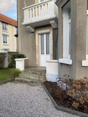 Un immeuble de deux étages avec une porte blanche et un balcon.