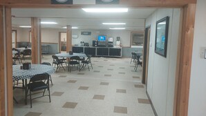 A cafeteria area with checkered tables and chairs, a counter with a coffee machine, and signs for the Armadillo Hotel.