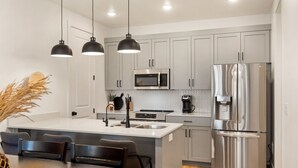 A modern kitchen with a central island, stainless steel appliances, and pendant lighting. - Sun & Fun #89 by RedAwning (St. George)