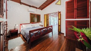 Ein Schlafzimmer mit einem Holzbett, einem Nachttisch, einer weißen Wand und einer roten Tür.