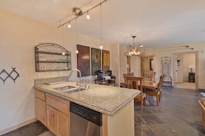 A modern kitchen with granite countertops, stainless steel appliances, and a dining area with wooden furniture. - 3 BR 2 BA Ski-in & Ski-out, 50 steps to ski run, unbelievable location! (Mammoth Lakes)