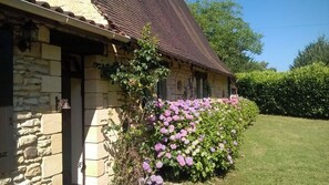 Set amidst a serene garden, this charming farmhouse offers an entrance and a tranquil atmosphere.