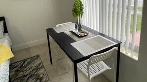A dining area with a table, chairs, a plant, and a window with blinds. -  Cozy suite with private entrance and parking! (Miami)