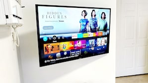 A flat-screen TV mounted on a wall displaying a streaming service interface with various content options. -  Cozy suite with private entrance and parking! (Miami)