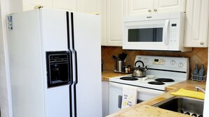 A kitchen with white cabinets, a white refrigerator, a microwave, a stove, and a sink. -  Cozy suite with private entrance and parking! (Miami)