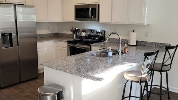 A modern kitchen with stainless steel appliances, a granite countertop, and a central island with bar stools. - SC (3745) 2BDR Townhouse Ft Jackson.   (Columbia)