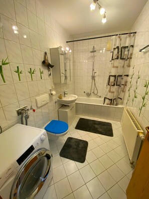 Un baño con lavadora, inodoro, lavamanos, bañera y ducha.