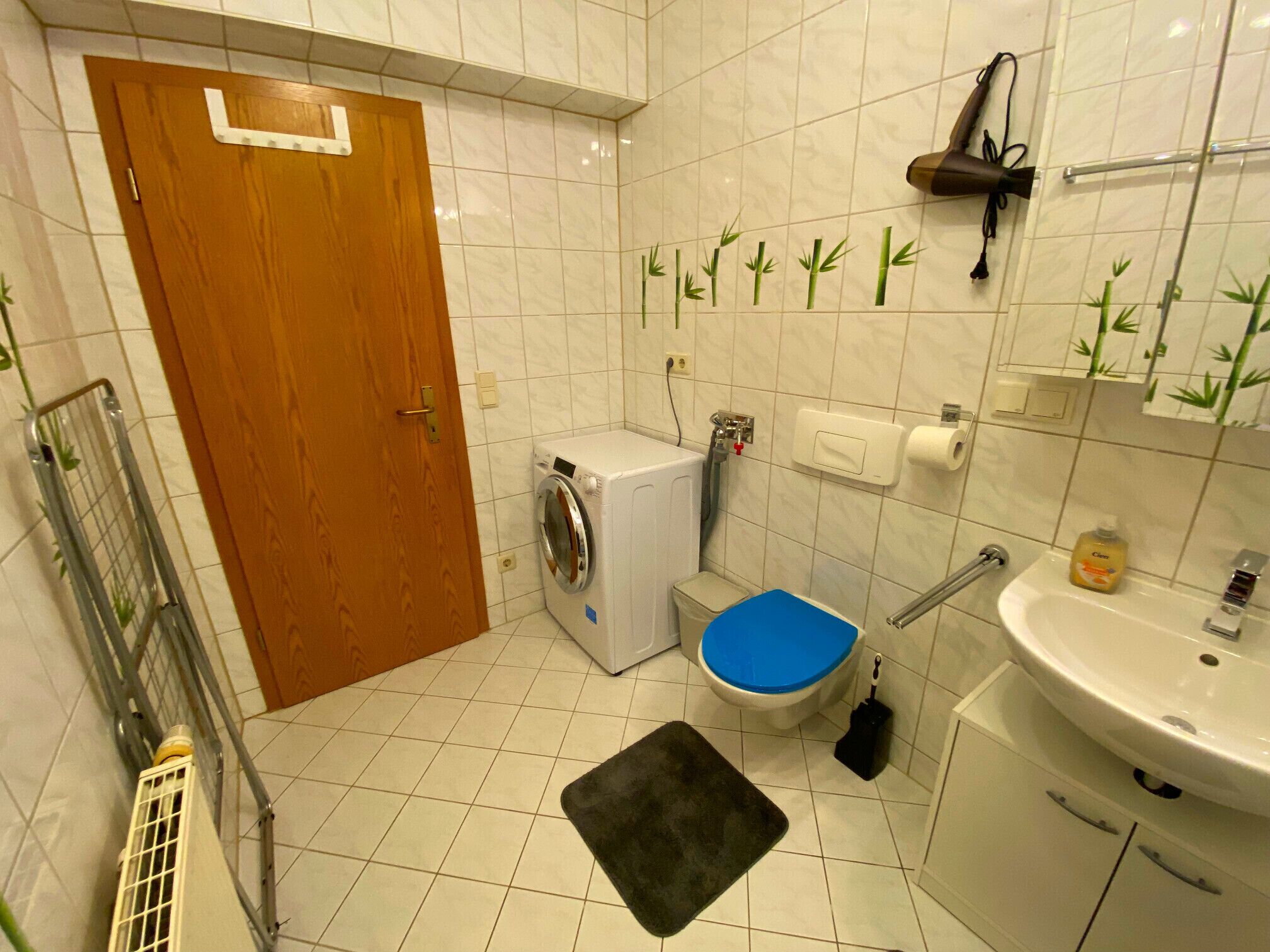 A compact bathroom with a washing machine, toilet, sink, and a shower area.