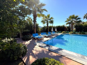 Una piscina al aire libre, sillones reclinables de piscina