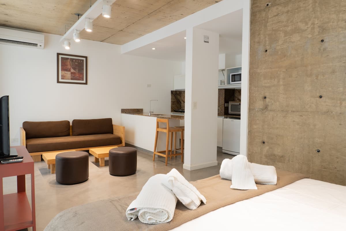Ein modernes Hotelzimmer mit einer Couch, einem Schreibtisch, einem Bett und einer Küchenzeile.