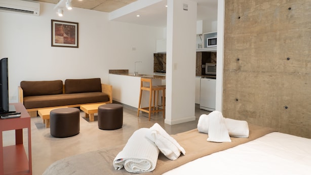 Une chambre d’hôtel moderne équipée d’un canapé, d’un bureau, d’un lit et d’une kitchenette.