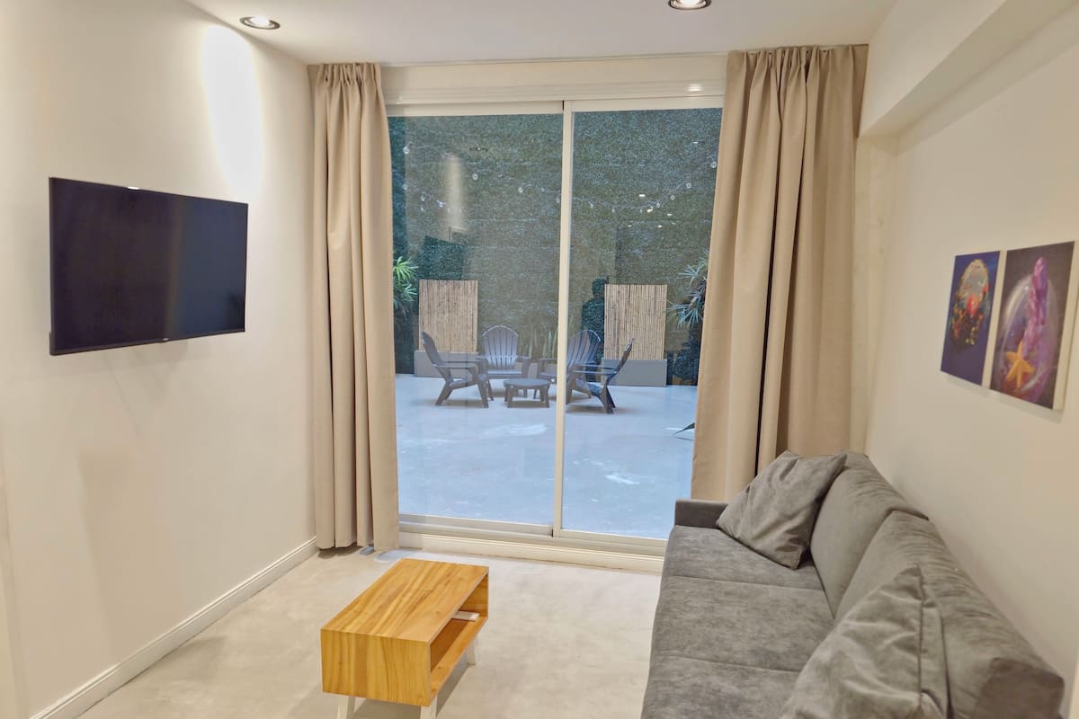 Ein modernes Wohnzimmer mit einem grauen Sofa, einem Holztisch und einem flachbildfernseher an der Wand.