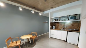 Une cuisine compacte avec un coin repas comprenant une table et des chaises, un four à micro-ondes et une machine à café.