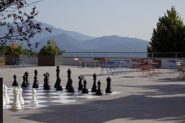Un tablero de ajedrez dispuesto al aire libre, con montañas al fondo.