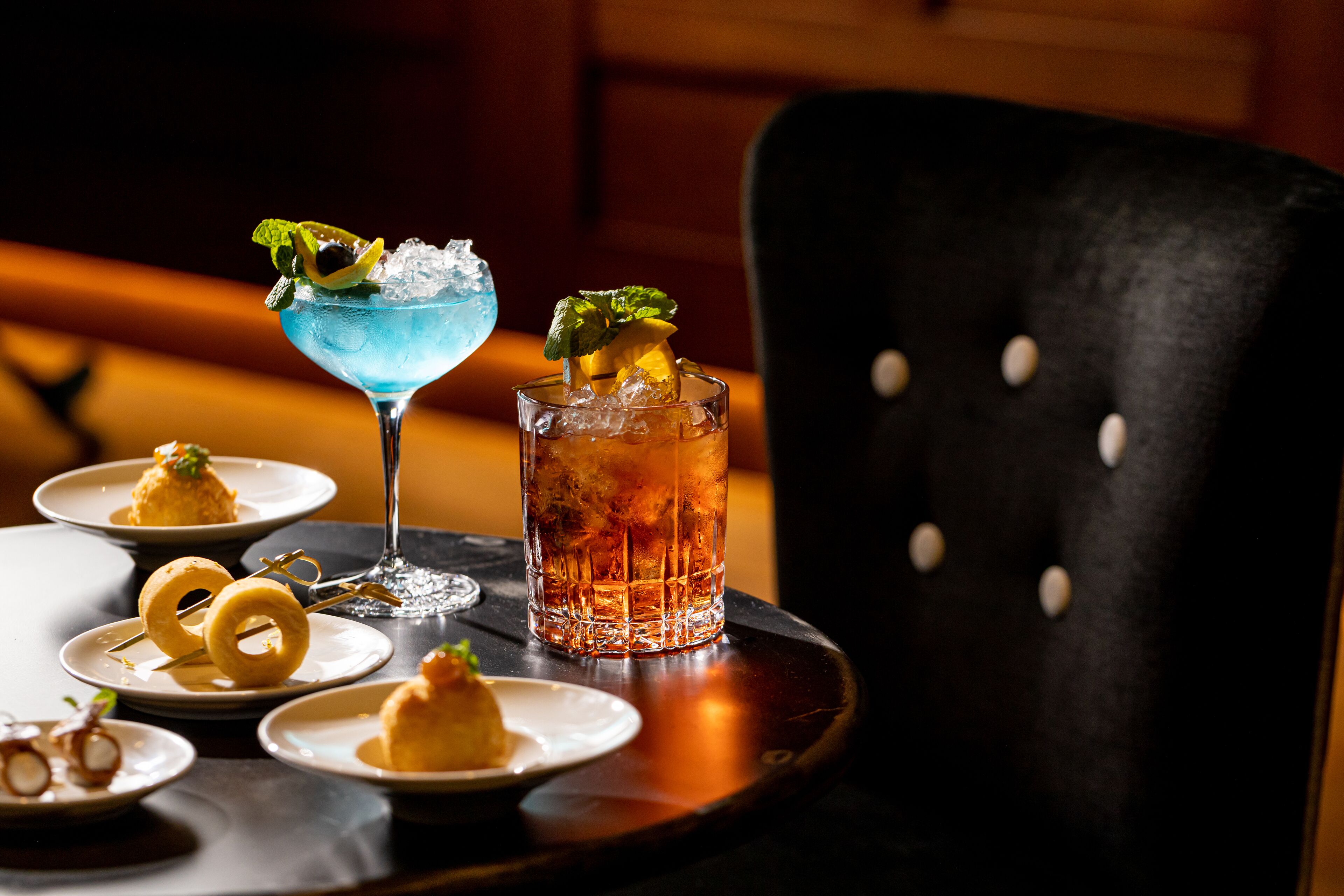 Ein Tisch mit einem Cocktail, einem Eistee und kleinen Schalen mit Essen.
