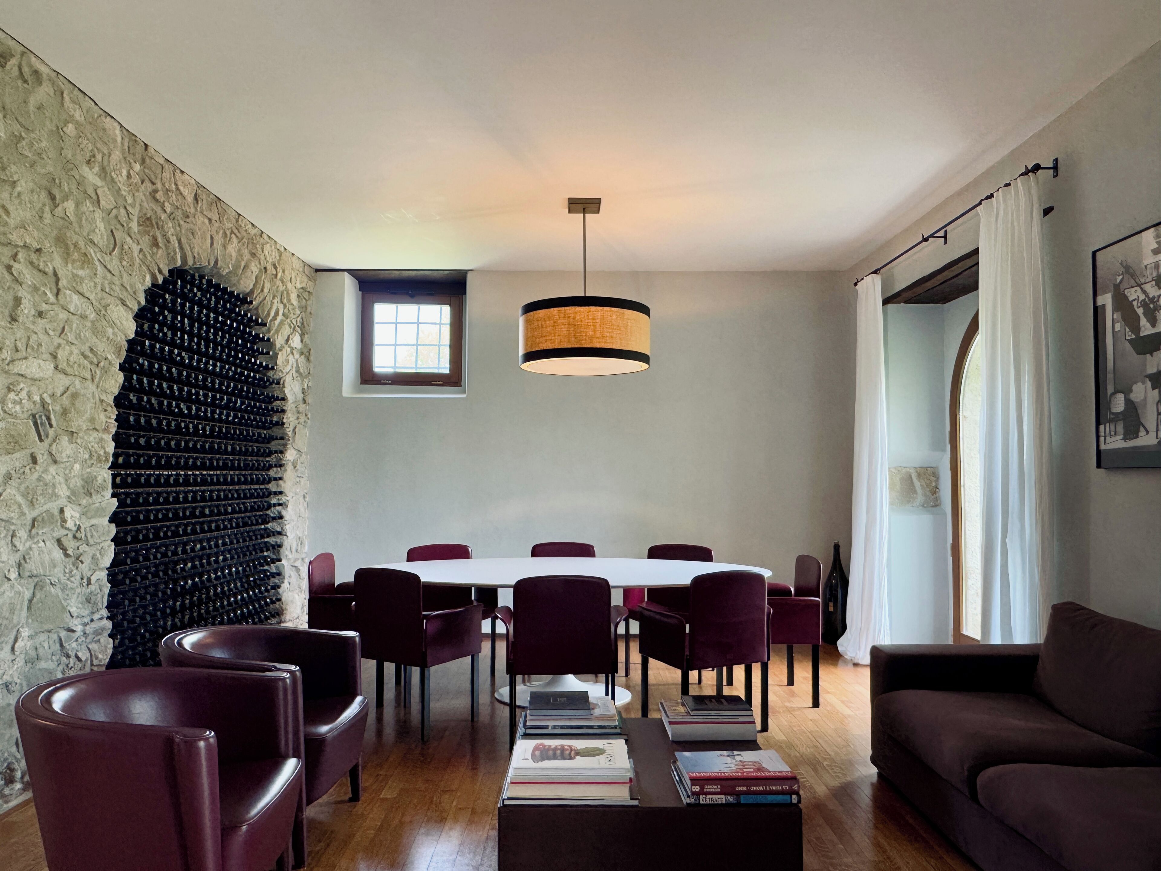 Un comedor moderno con pared de piedra, una mesa redonda y sillas rojas.