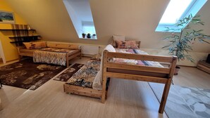 Ett sovrum på entresolplan med två våningssängar i trä, ett takfönster, en krukväxt och en liten hylla med dekorativa föremål.