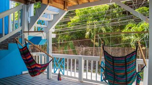 A wooden deck with two hammocks hanging from the ceiling.