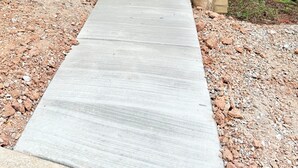 Eine Holzterrasse führt zu einer Holzhütte mit einer Metalttür, umgeben von Bäumen.