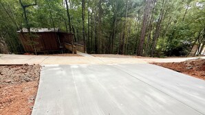 Eine gepflasterte Terrasse mit Holzdeck und einer kleinen Hütte inmitten eines bewaldeten Geländes.