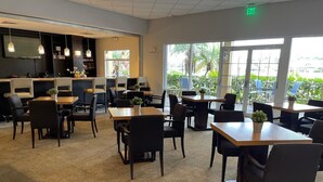 A restaurant with multiple tables and chairs, a bar area, and large windows with a view of the outdoors. - Only 5 minutes from Walt Disney World (Kissimmee)