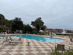 Relax by the pool surrounded by lounge chairs and tables, with umbrellas and a gazebo providing shade.