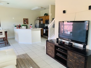 Relax in this stylish living room with a large flat-screen TV, island, and kitchen area.